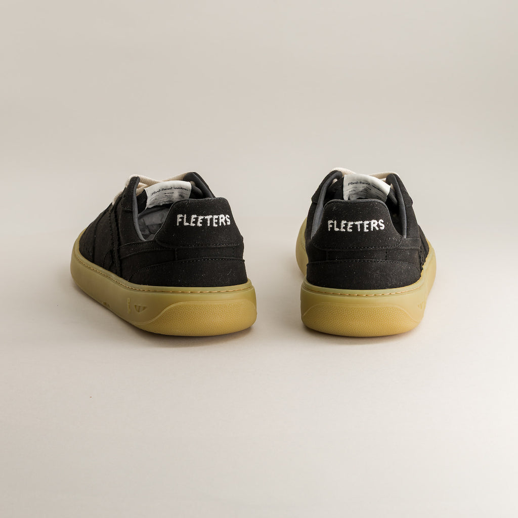 Black barefoot sneakers with yellow soles on a light gray background