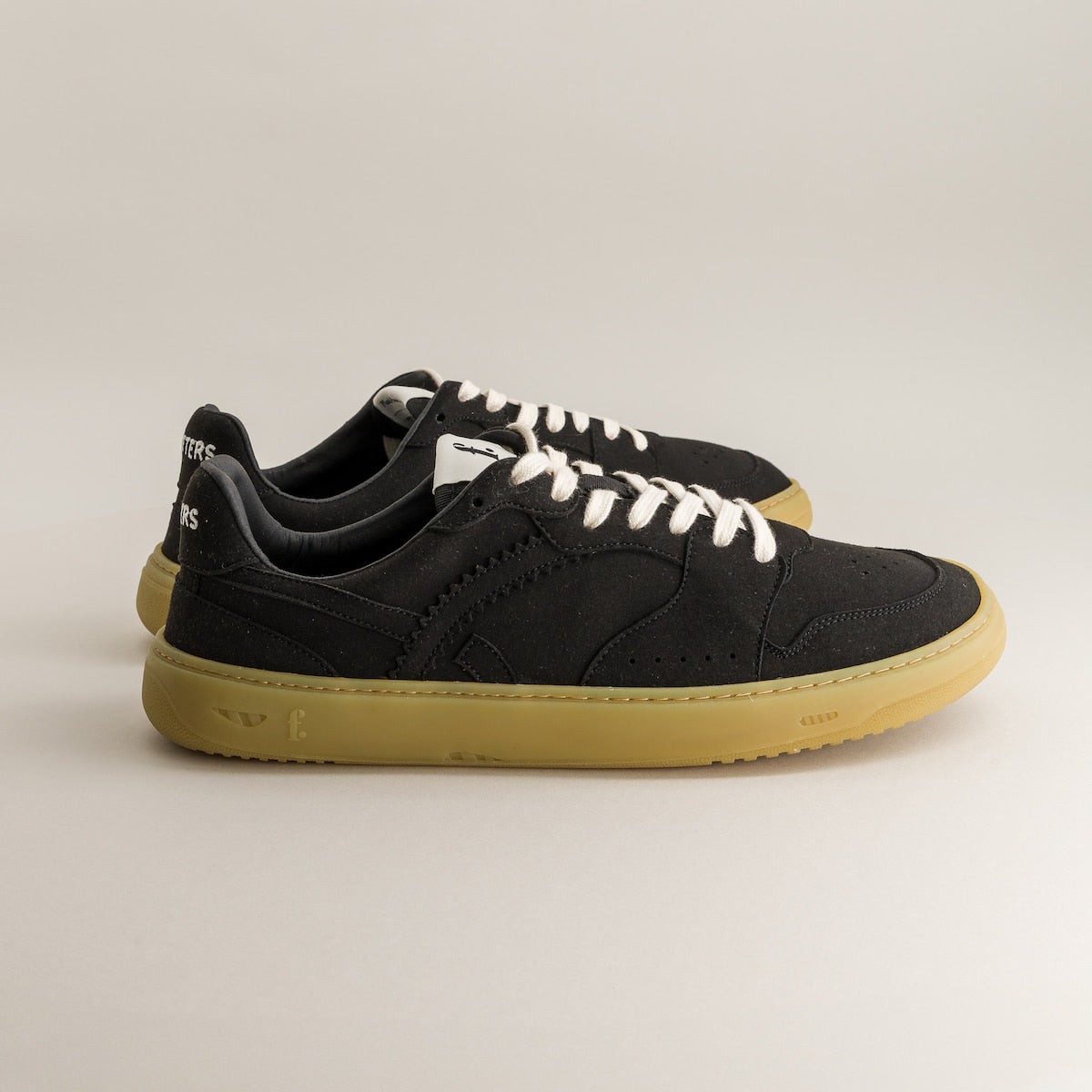 Black barefoot sneakers with white laces on a light gray background