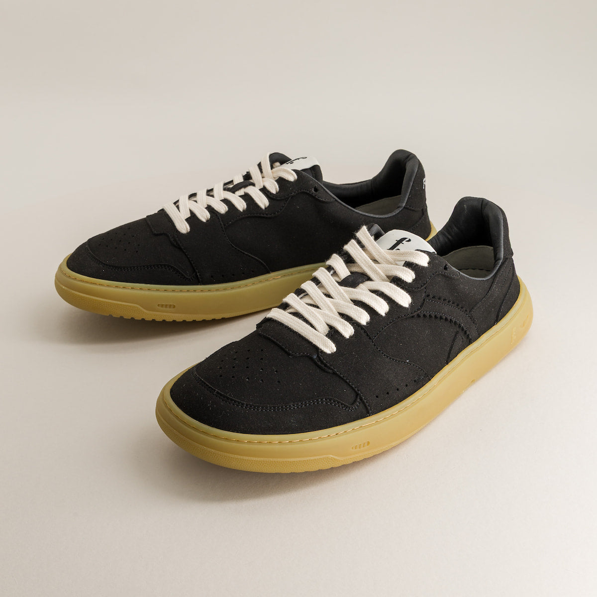 Black barefoot sneakers with white laces on a light gray background