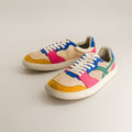Colorful sneakers with a beige, blue, pink, and yellow design on a light gray background