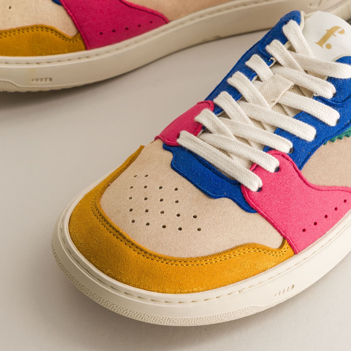 Colorful sneaker with pink, blue, and yellow accents on a light background