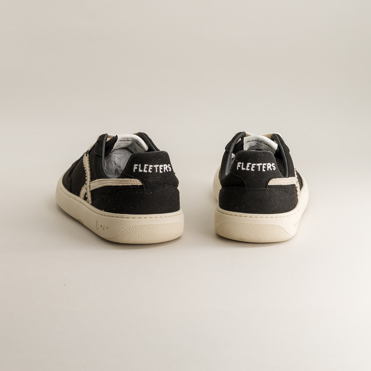 Black sneakers with 'Fleeters' branding on a light gray background