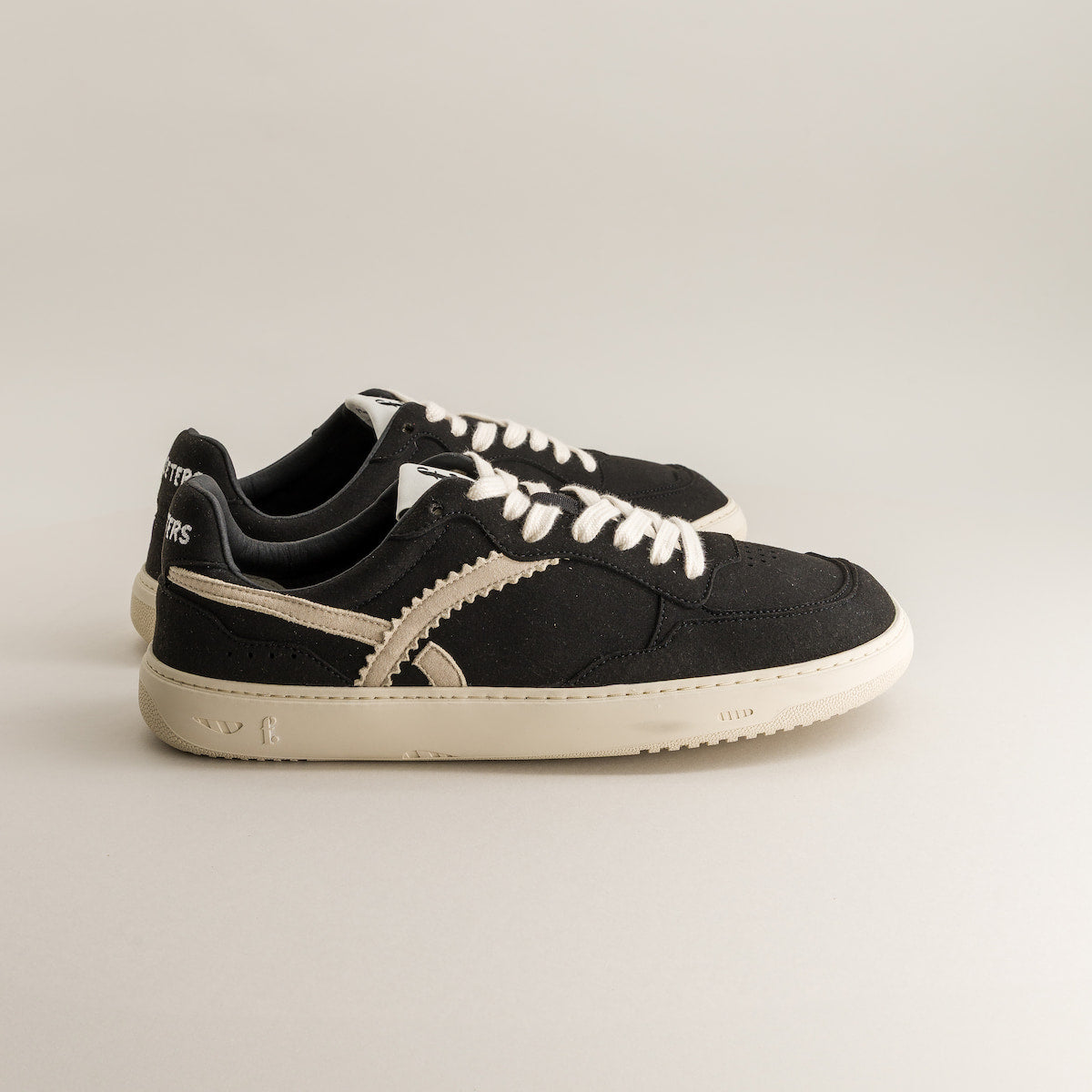 Black sneakers with white laces on a light gray background