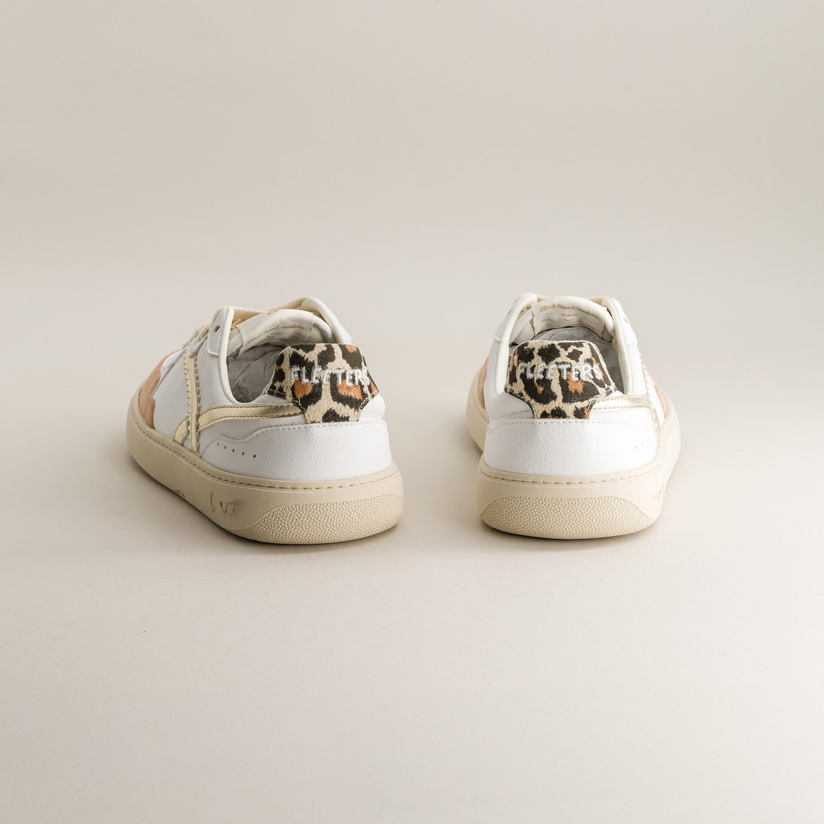 Pair of white barefoot sneakers with leopard print accents on a light gray background