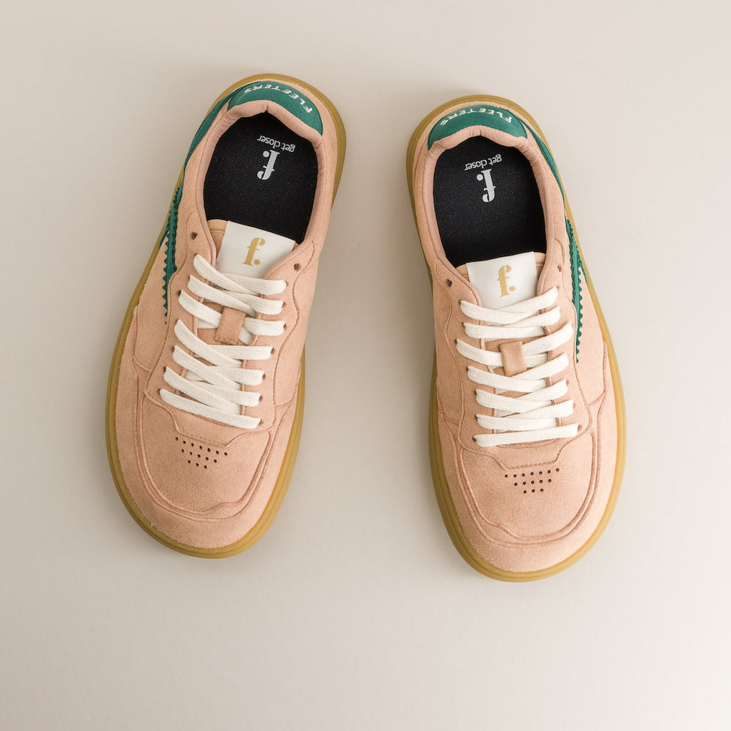 Pair of pink sneakers with white laces on a beige background