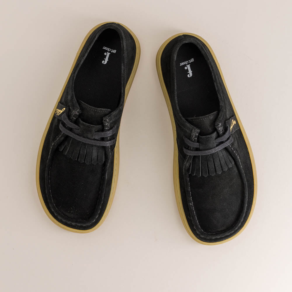 Pair of black loafers with tassels on a beige background