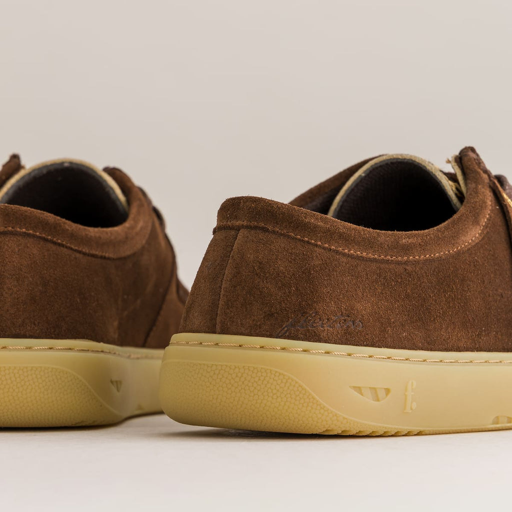 Brown suede shoes with beige soles on a light gray background