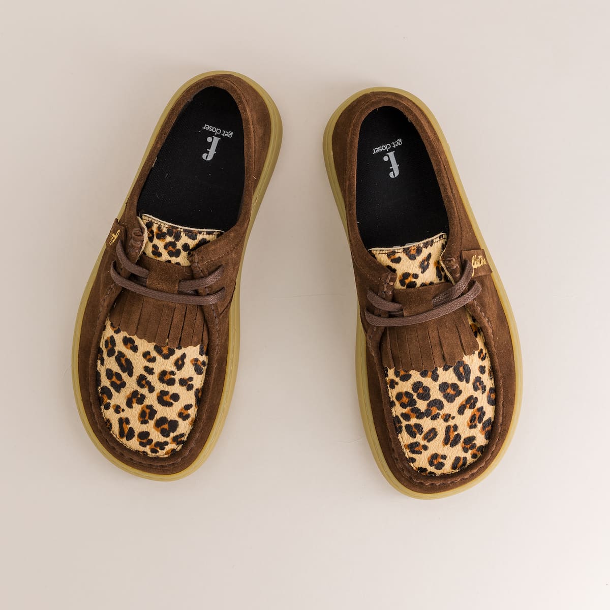 Pair of brown derby with leopard print soles on a light background