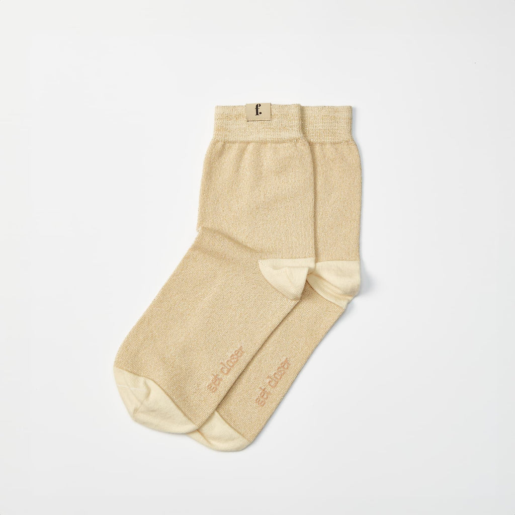 A pair of light beige barefoot socks with a contrasting cream toe and heel, laid flat on a clean white background. 