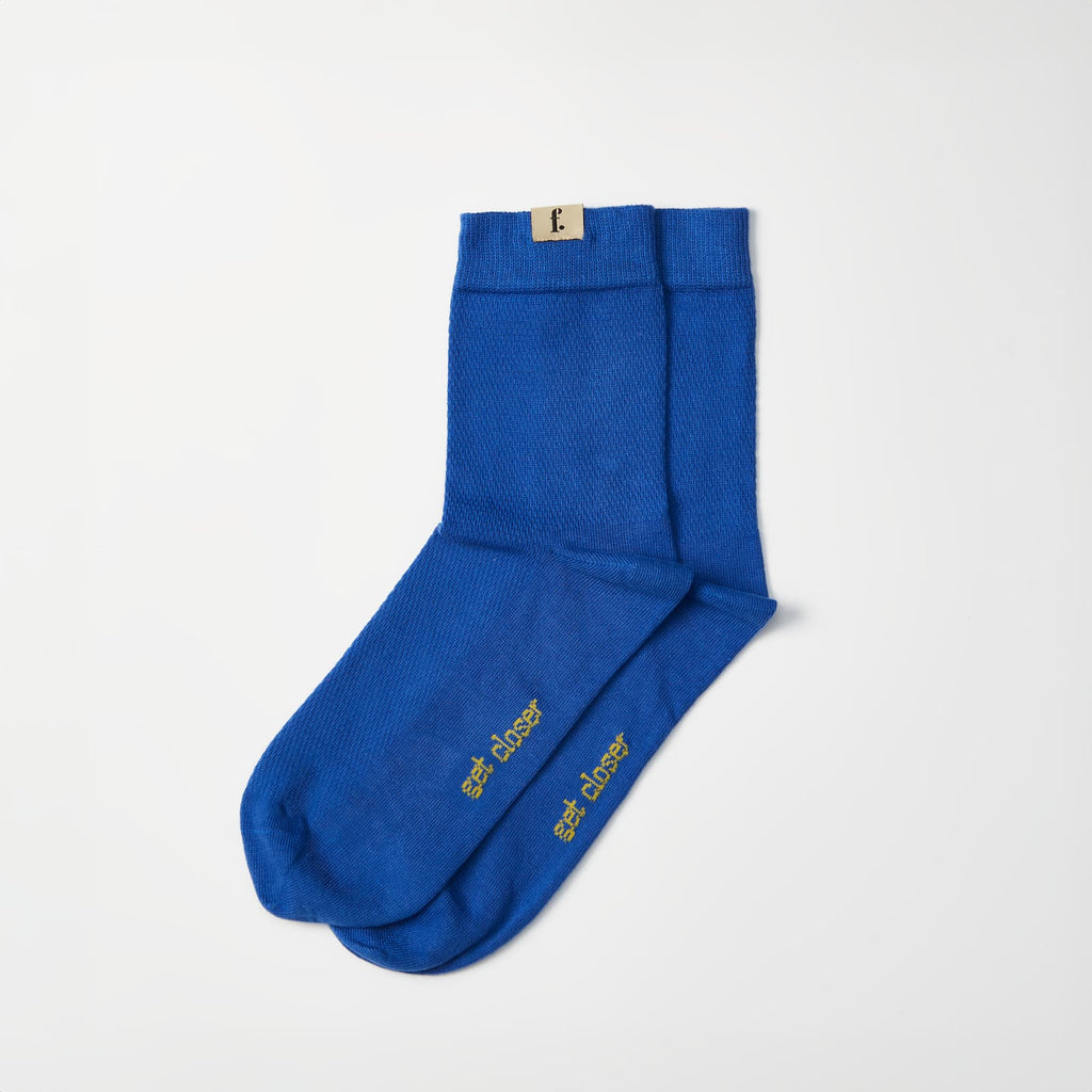 A pair of royal blue barefoot socks with gold 'get closer' text printed on the soles, displayed on a clean white background.