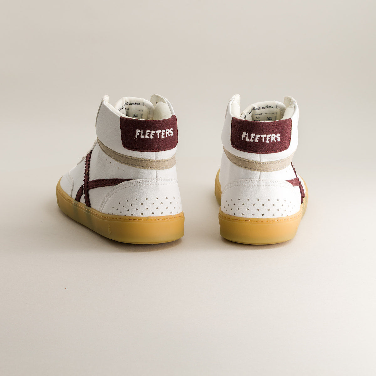 Pair of white mid-ankle barefoot sneakers with maroon accents and 'Fleeters' branding on a light background