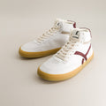 White high-top barefoot sneakers with maroon accents on a beige background