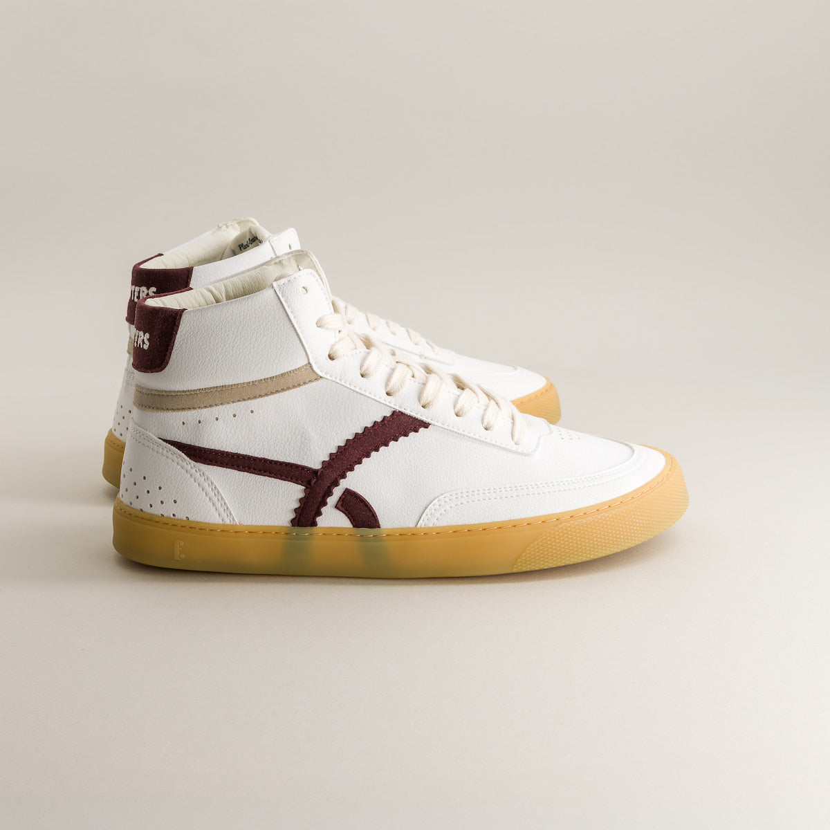 White high-top barefoot sneakers with brown accents on a light gray background