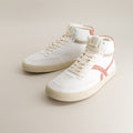 White mid-ankle barefoot sneakers with pink accents on a beige background