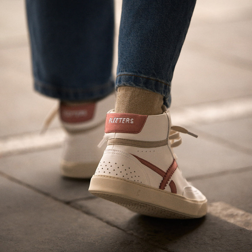 person wearing a Pair of white mid-ankle barefoot sneakers with pink accents 