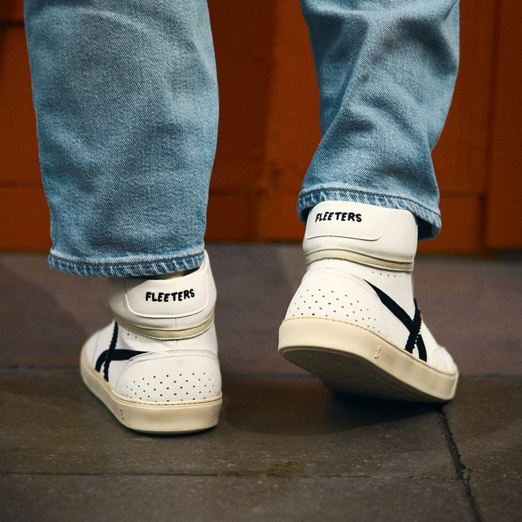 person wearing White high-top barefoot sneaker with black design 